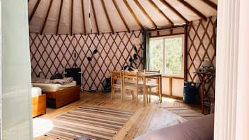 A cozy interior with a wooden floor, a bed, a table, and a window.