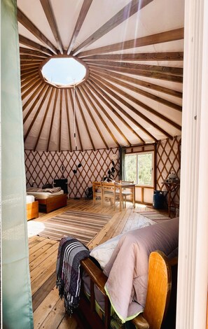 A cozy interior with a wooden floor, a bed, a table, and a window.
