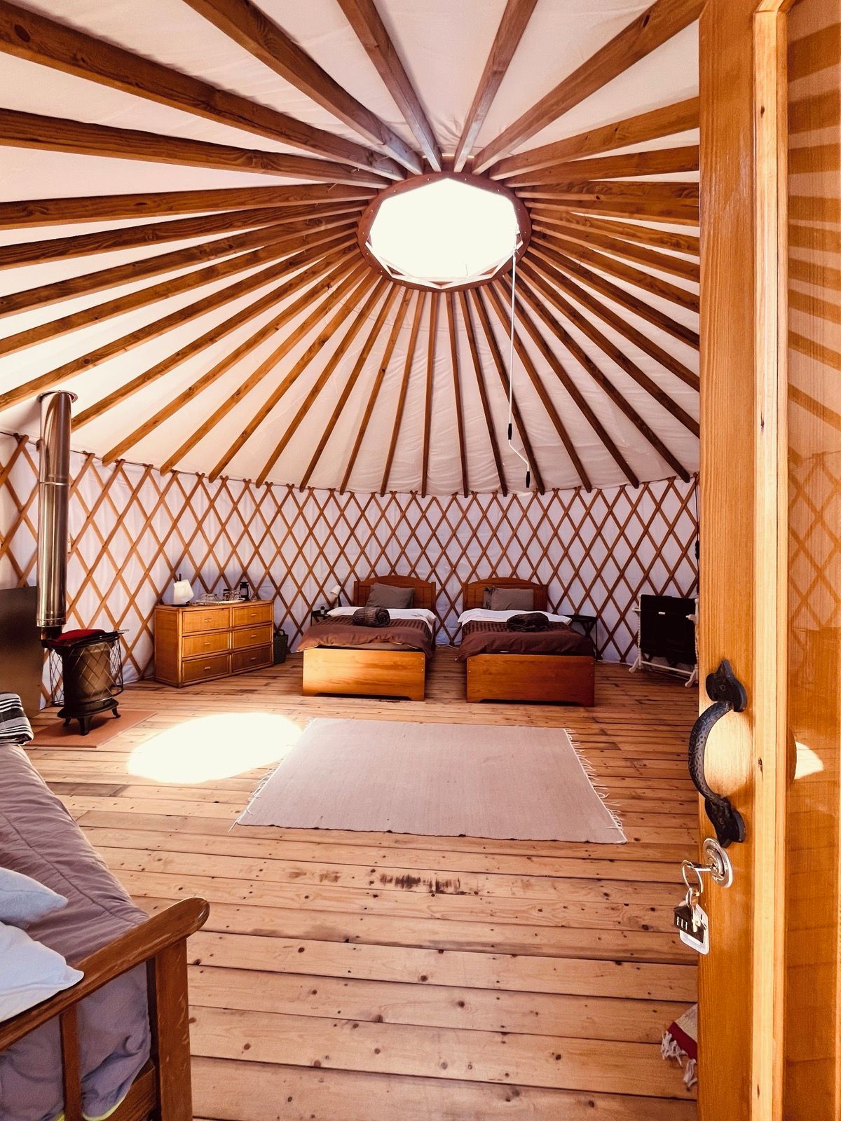 A cozy room with a sloped ceiling, wooden flooring, two beds, a heater, and a window.
