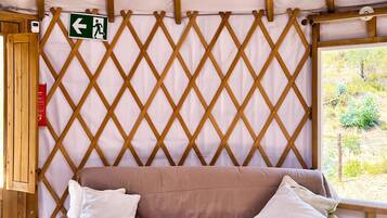 A wooden sofa with cushions, a lattice wall, and a view of greenery outside.