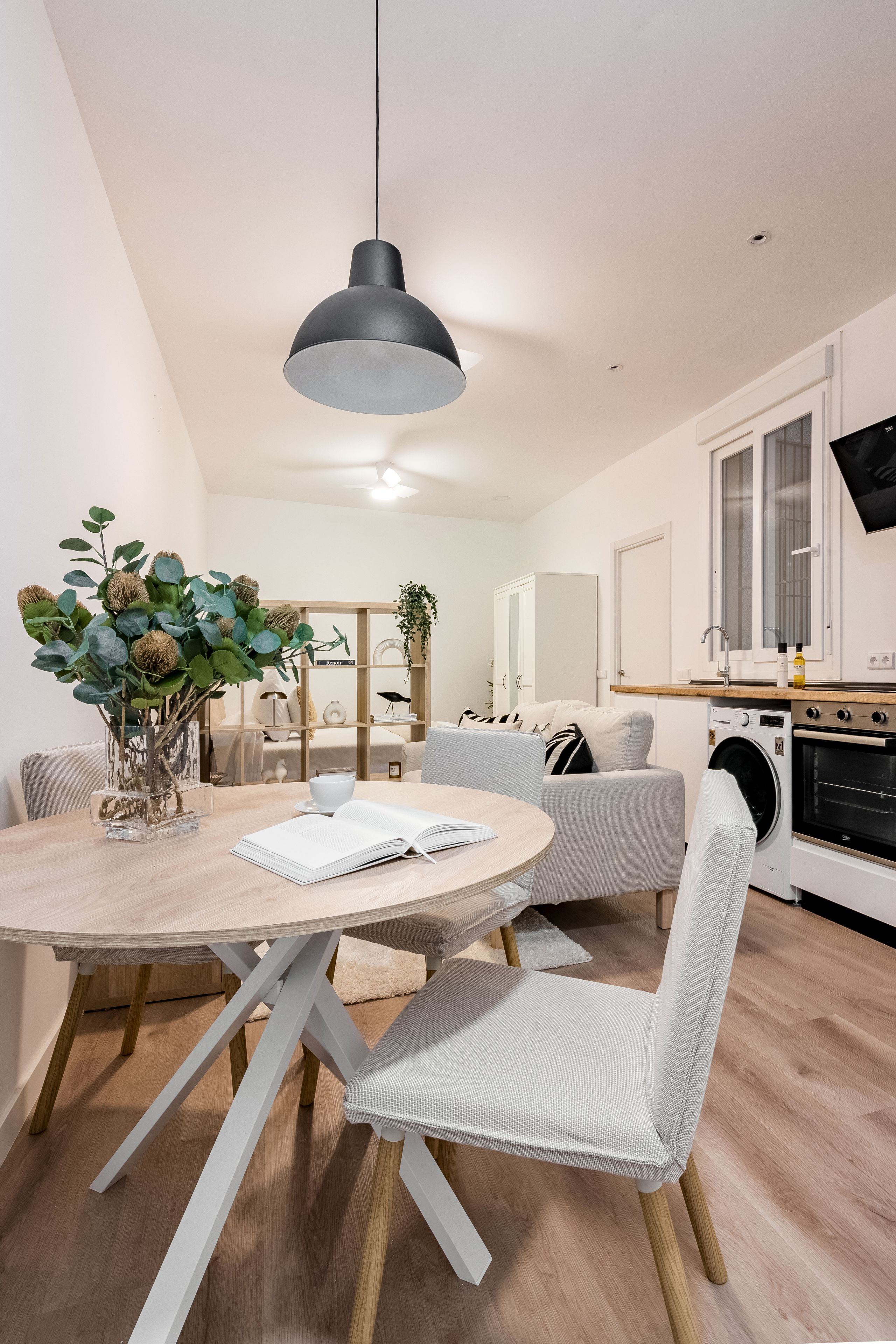 Una cocina moderna con horno integrado, un comedor con mesa redonda y un conjunto de asientos.