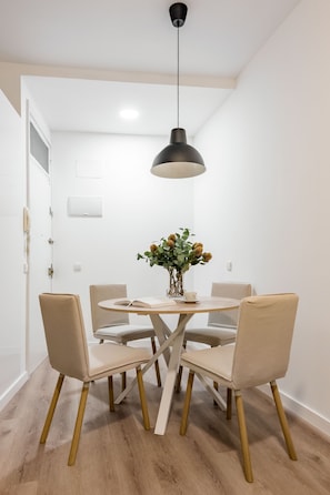 A dining area with a round table, four chairs, a vase with flowers, and a pendant light. - Newly renovated in the heart of Madrid (Madrid)