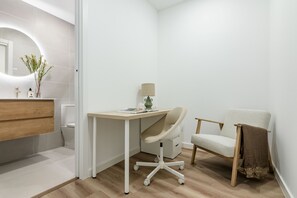 A modern bathroom with a wooden vanity, a white toilet, a desk with a chair, and a mirror with a light. - Newly renovated in the heart of Madrid (Madrid)