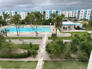 Ein Hotel mit Schwimmbad, Palmen und einem Parkplatz.