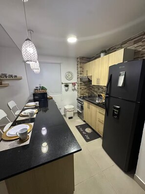 Eine moderne Küche mit schwarzem Arbeitsplatz, einem Kühlschrank und einem Herd.