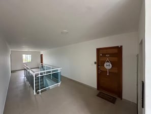 A hallway with a glass railing, a wooden door with a number, and a small window. - Punta Cana Paraiso Tropical Playas de Mar Caribeño (Punta Cana)