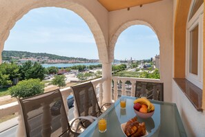 Ein Balkon mit Frühstückstisch, mit Blick auf eine Küstenstadt.