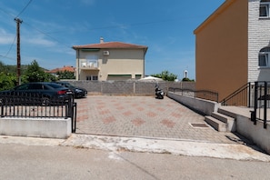 Un barrio residencial con un camino pavimentado que lleva a una casa con techo de tejas rojas.