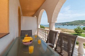 Ein Balkon mit Frühstückstisch, der auf ein Gewässer und eine Brücke blickt.