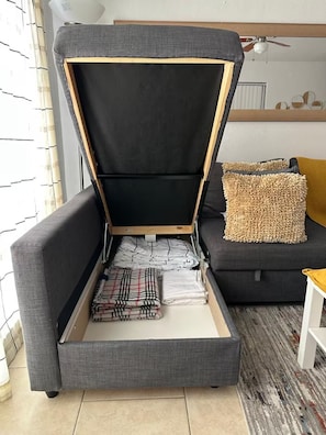 A room with a grey sofa, a black and white patterned blanket, and a beige textured pillow.