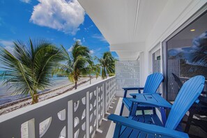 A balcony with a view of the beach, two blue chairs, and a white railing. - Oceanfront Key Colony Beach Condo with Private Balcony, Sandy Shoreline & Sweeping Atlantic Views (Key Colony Beach)