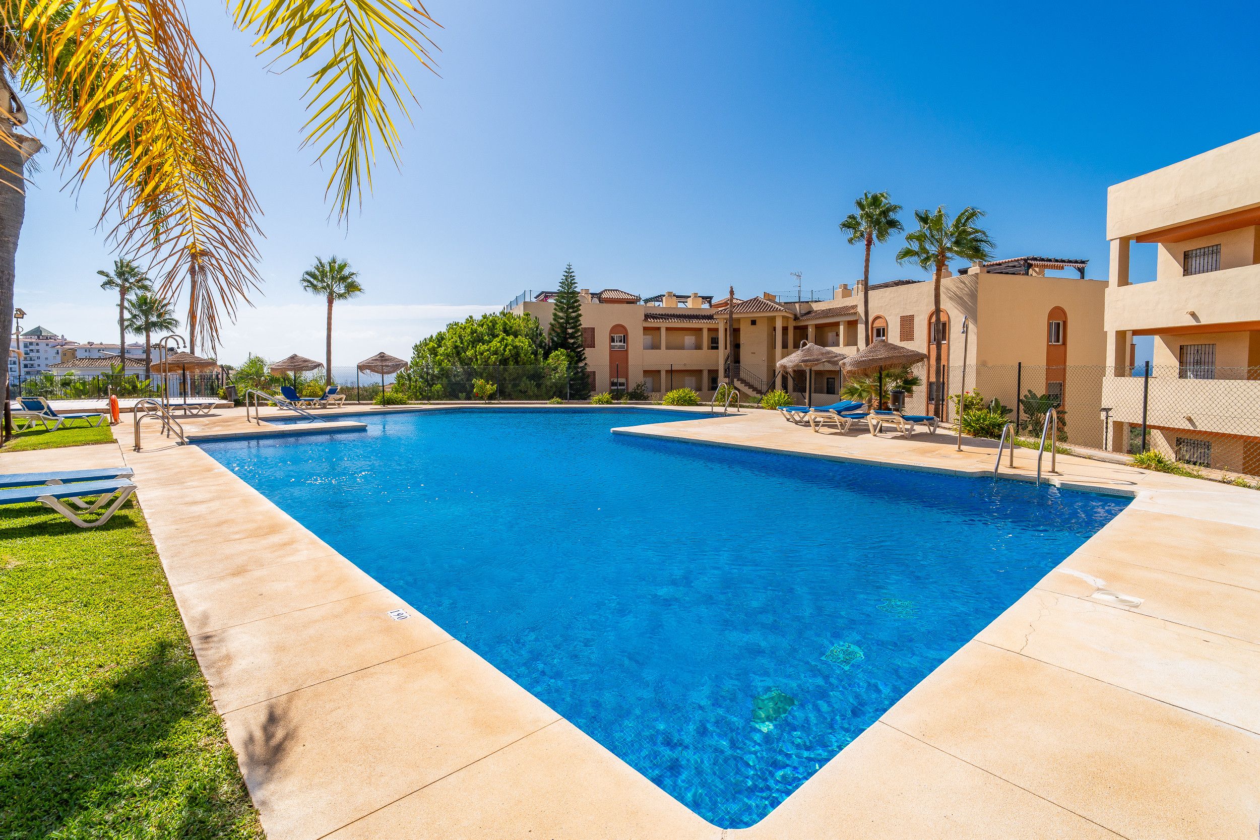 A rectangular swimming pool with a clear blue water surface, surrounded by a paved deck.