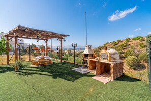 A patio area with a brick oven, a pergola with hanging planters, and a view of the sea. - Cubo's Opalo de Riviera Apartment / communal pool / communal gym / air conditioning / terrace (Mijas Costa)