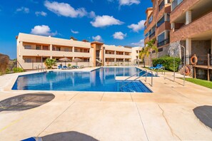 A swimming pool with lounge chairs and a lifebuoy, surrounded by multi-story buildings. - Cubo's Opalo de Riviera Apartment / communal pool / communal gym / air conditioning / terrace (Mijas Costa)