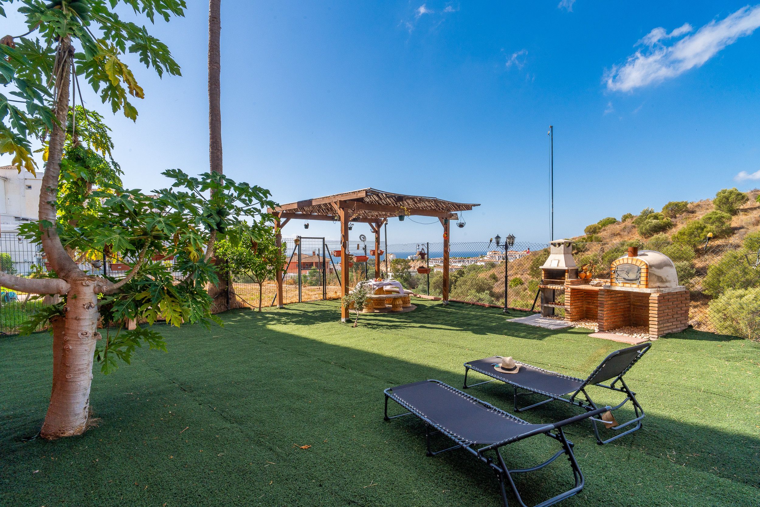 A patio with a pergola, outdoor seating, and a barbecue area.
