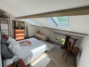 A bedroom with a skylight, a bed, a dresser, a chair, and a small table. - A night under a starry sky in the peaceful countryside at the foot of the mountains. (Castellet-lès-Sausses)