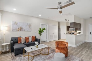 A modern living room with a grey sofa, a coffee table, and a ceiling fan. - 2-bedroom apartment in adorable Dallas with cool AC and gym access (Dallas)