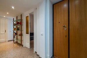 A hallway with a wooden door, a glass shelf unit, and a carpeted floor. - Principe 37 - Charme Holidays (Rome)