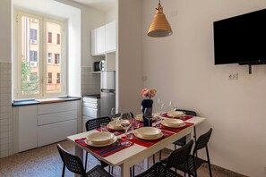 Eine moderne Küche mit weißen Schränken, einem eingebauten Backofen und einem Fenster mit Blick auf ein Gebäude.