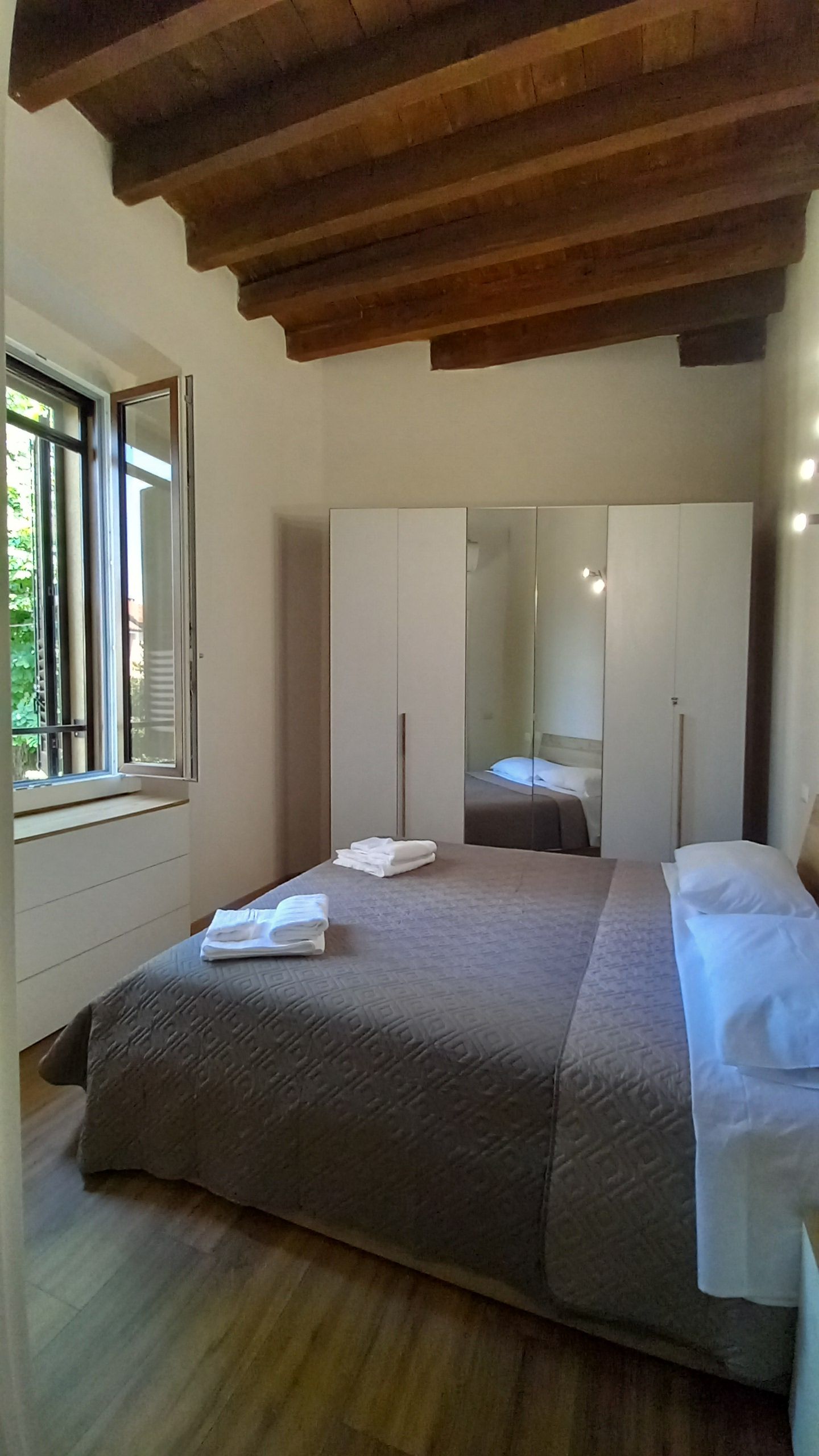 Una camera da letto con un letto, uno specchio grande e una finestra.