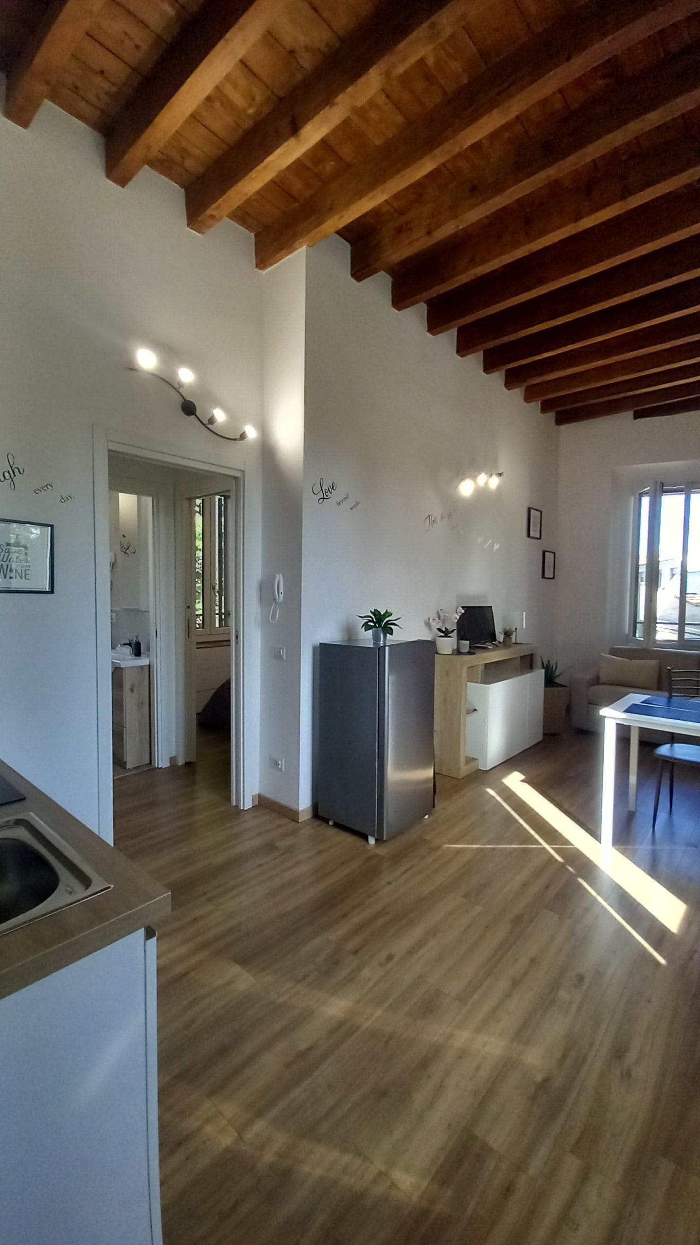 Cucina spaziosa con travi in legno, un frigorifero e un'area pranzo con tavolo e sedie.