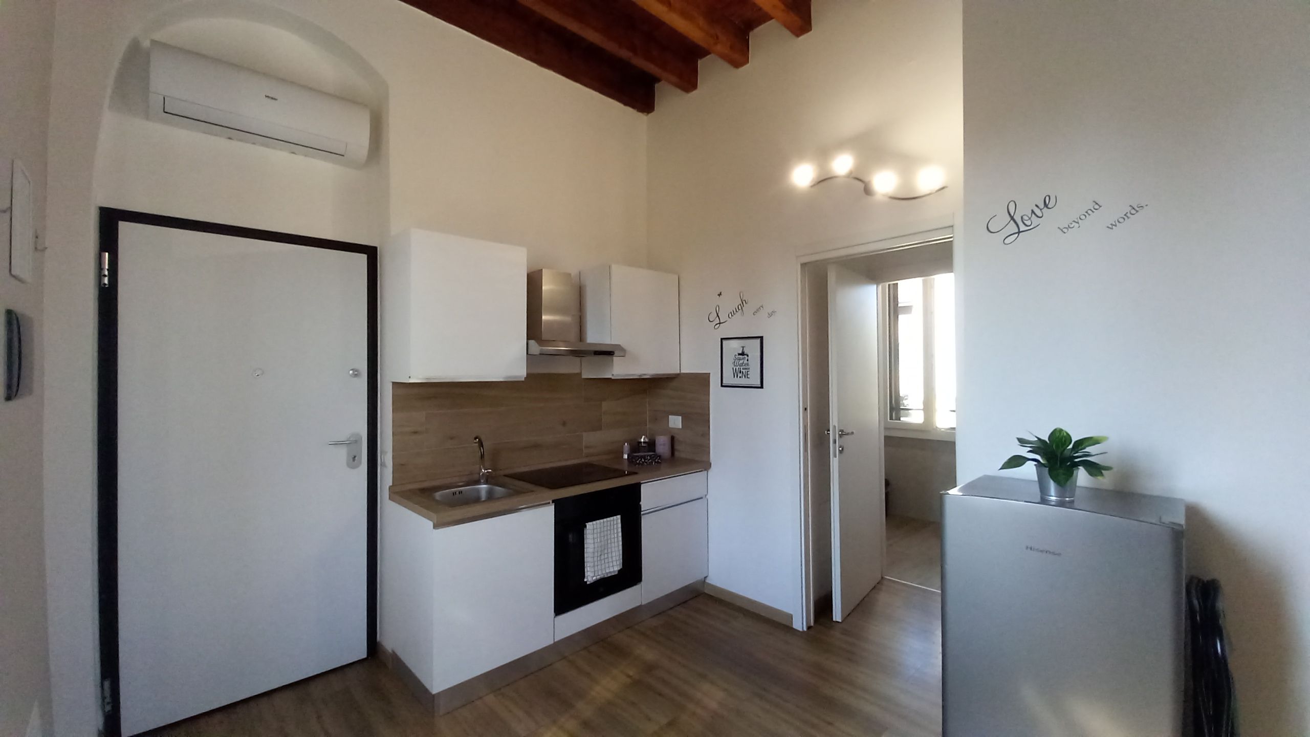 Una cucina con forno a incasso, lavello e frigorifero in acciaio inox.