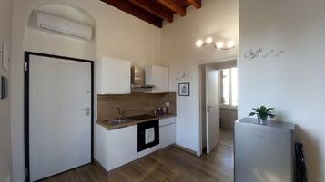 Una cucina con forno a incasso, lavello e frigorifero in acciaio inox.