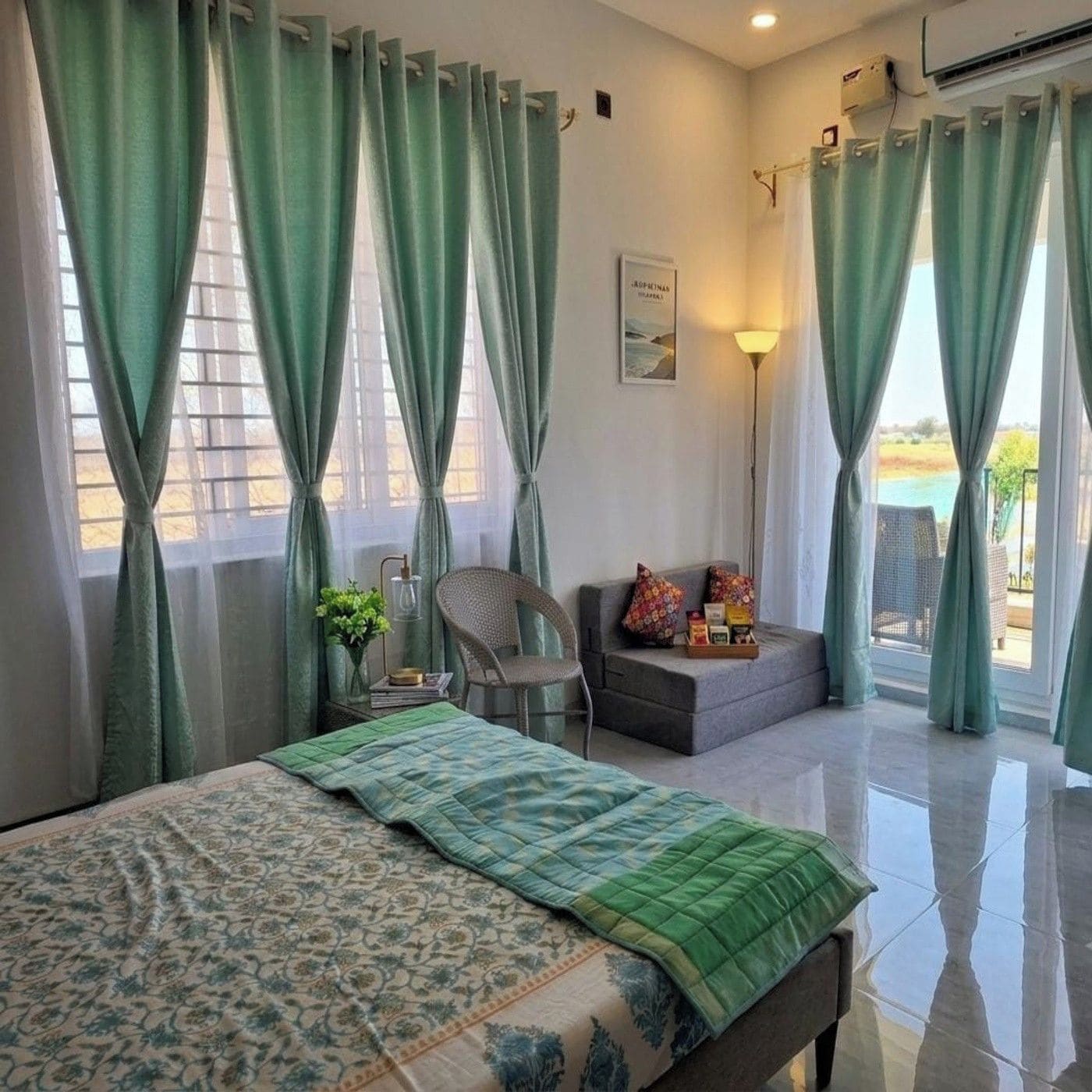 A bedroom with a bed, a chair, a sofa, and a view of the outdoors.