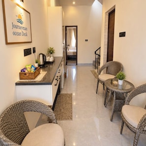 A hotel room with a kitchenette, wicker furniture, and a framed sign on the wall.