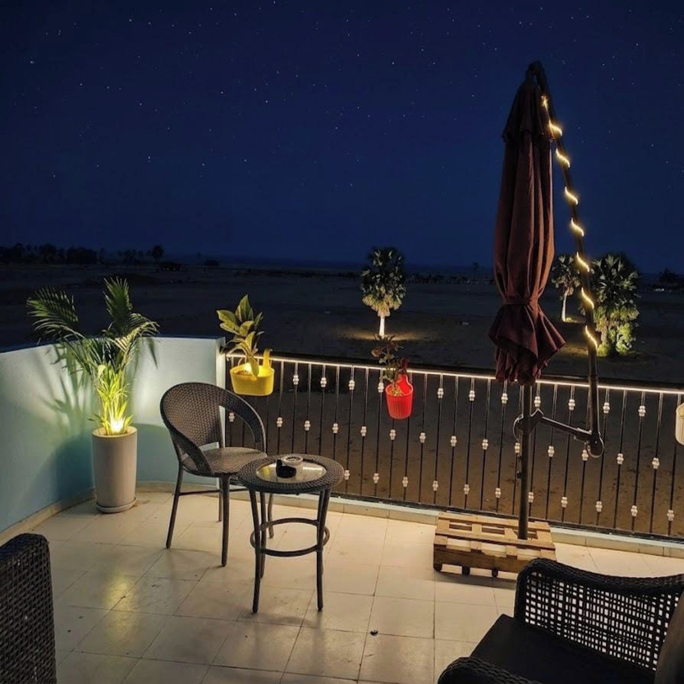 A balcony with a chair, a small table, and potted plants.