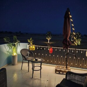 A balcony with a chair, a small table, and potted plants.