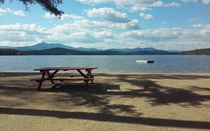 A picnic table by a lake with mountains in the background. - Camp Come Again on Silver Lake–Pet-Friendly w/ Private Dock, Swimming & Views (Silver Lake)