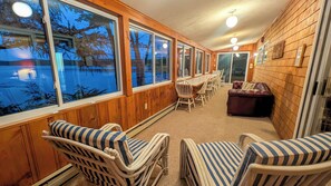 A room with large windows, wooden walls, a dining table with chairs, and a leather sofa. - Camp Come Again on Silver Lake–Pet-Friendly w/ Private Dock, Swimming & Views (Silver Lake)