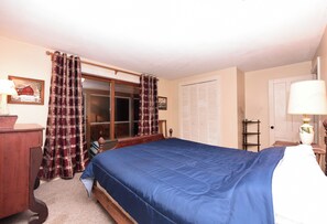 A bedroom with a bed, a dresser, a window with curtains, a door, and a lamp. - Camp Come Again on Silver Lake–Pet-Friendly w/ Private Dock, Swimming & Views (Silver Lake)