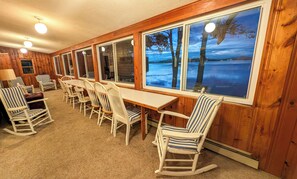 A cabin with a long dining table and striped chairs, large windows with a view of a lake, and a ceiling with round lights. - Camp Come Again on Silver Lake–Pet-Friendly w/ Private Dock, Swimming & Views (Silver Lake)