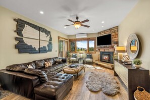 A modern living room with a leather sofa, a fireplace, and a stone wall. - Steps to the Lifts | Hot Tubs, Fireplace & Shuttle (Steamboat Springs)