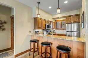 A kitchen with wooden cabinets, stainless steel appliances, and a granite countertop. - Steps to the Lifts | Hot Tubs, Fireplace & Shuttle (Steamboat Springs)