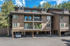 A multi-story residential building with a garage, balconies, and a clear sky. - Cozy 1BR Ski Condo | Fireplace + Shuttle to Slopes (Steamboat Springs)