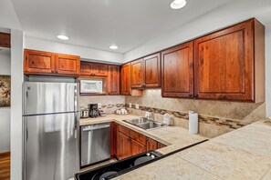 A kitchen with wooden cabinets, stainless steel appliances, and a tiled backsplash. - Cozy 1BR Ski Condo | Fireplace + Shuttle to Slopes (Steamboat Springs)