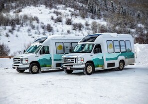 Zwei weiße Wohnmobile auf verschneierter Fläche vor einer Bergkulisse.