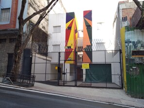 A building with a gated entrance, a tree in front, and a colorful vertical banner.