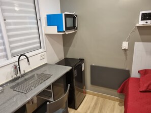 A compact kitchenette with a sink, microwave, and small refrigerator.