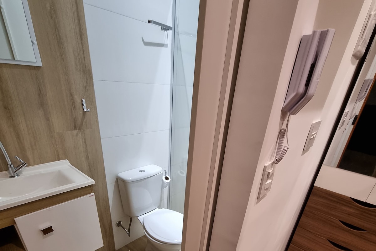 Une salle de bain avec un meuble-lavabo en bois, des toilettes et un espace douche.