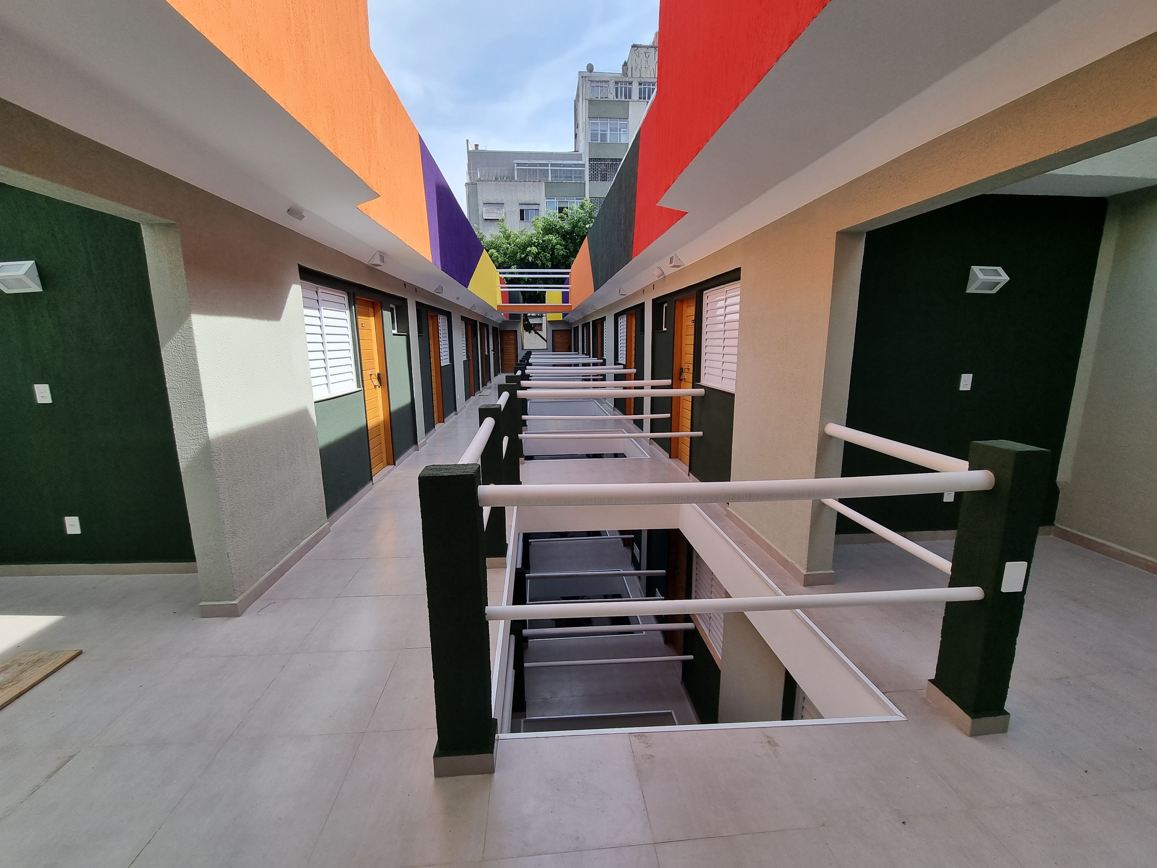Un couloir avec une allée centrale, bordé de portes et de fenêtres, qui mène à un bâtiment au design moderne.