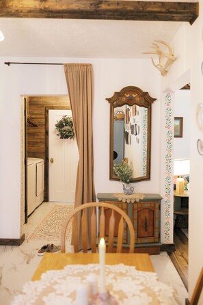 A room with a wooden door, a mirror, a vase with flowers, and a table with a lace tablecloth. - Historic Cottage Near PMC, UPIKE and Arena (Pikeville)