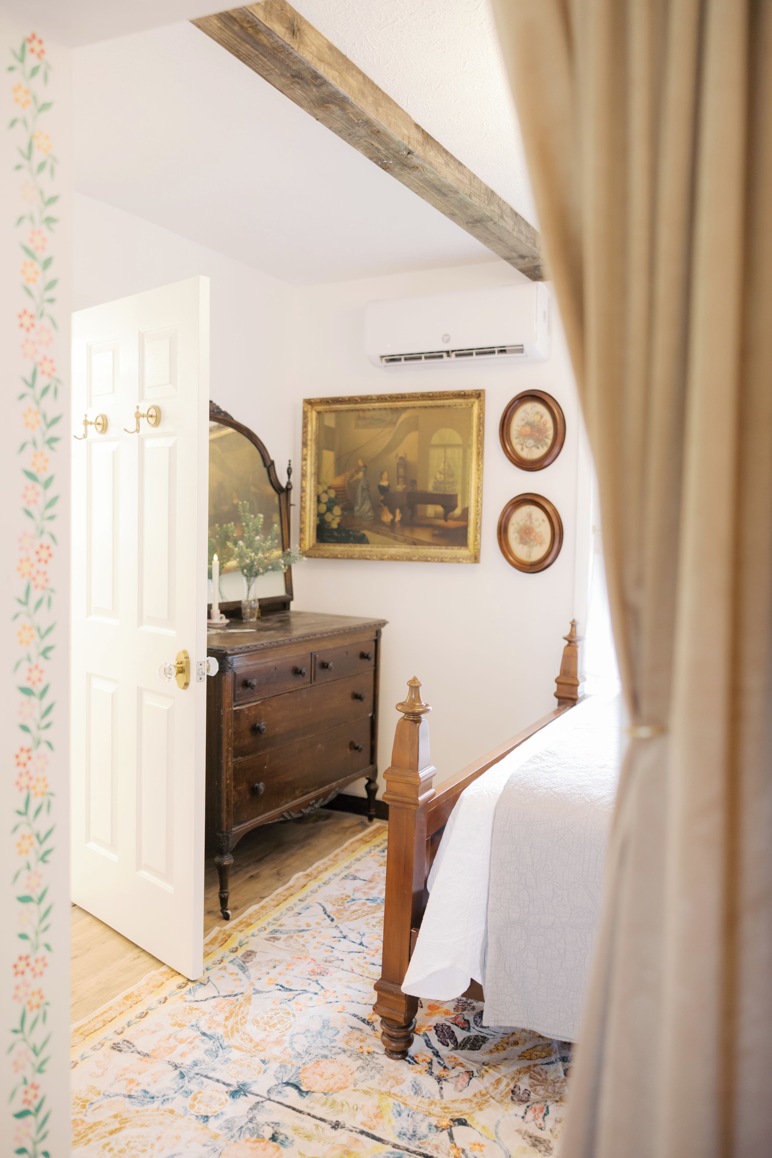 Une chambre à coucher avec un lit en bois, une commode, un miroir et un tableau accroché au mur.