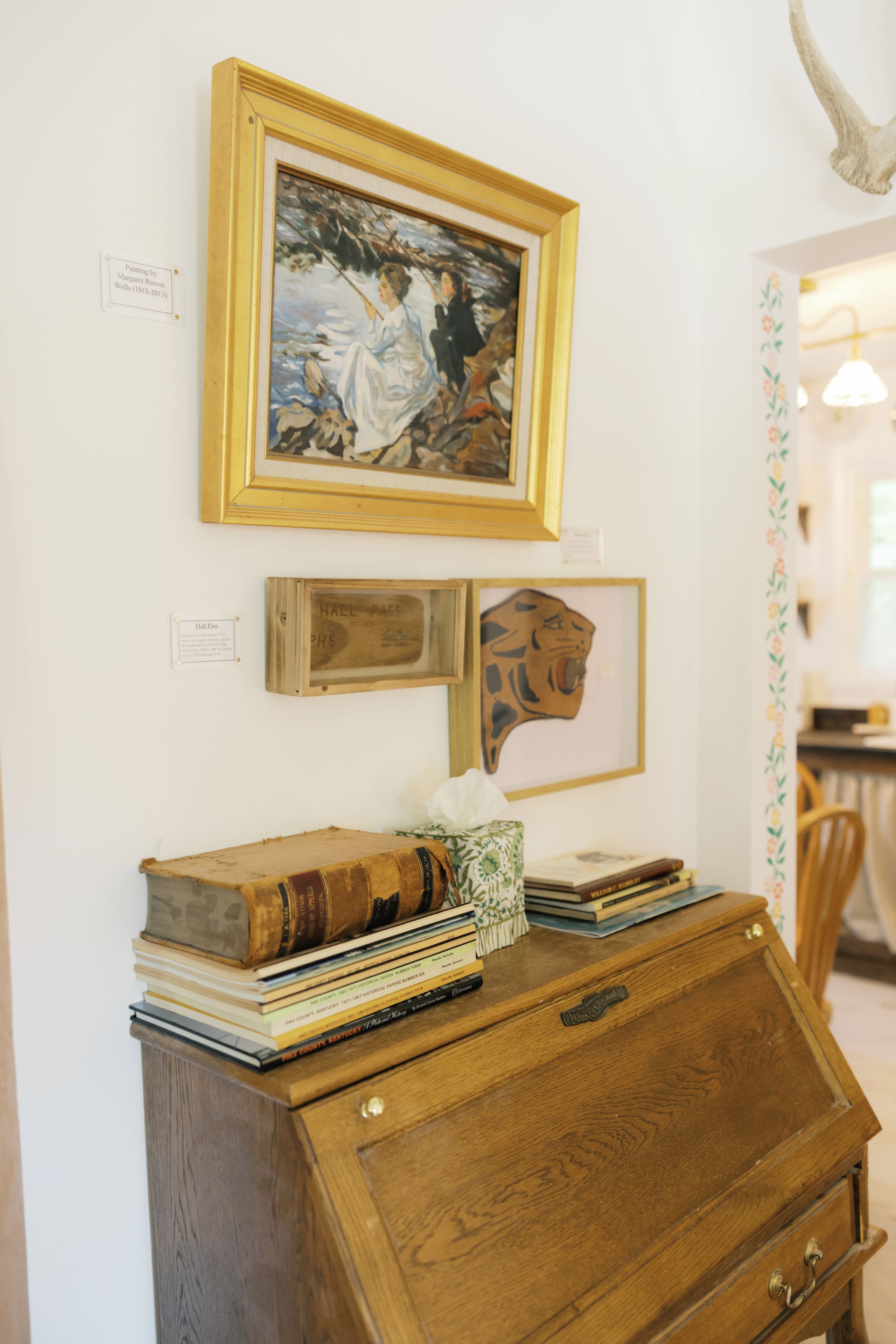 Un meuble en bois, avec des livres et des œuvres d’art encadrées accrochées au mur.