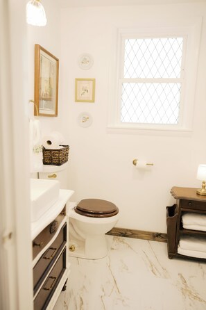 A bathroom with a toilet, sink, and a window with a mesh screen. - Historic Cottage Near PMC, UPIKE and Arena (Pikeville)