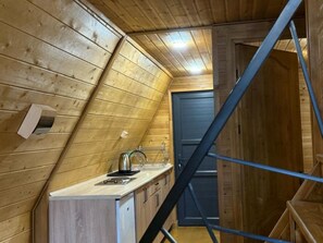 A small kitchenette with a sink, a kettle, and cabinets.