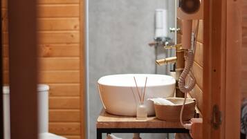 Un baño con detalles de madera, un lavamanos blanco, un abanico de mano y una pequeña cesta tejida.